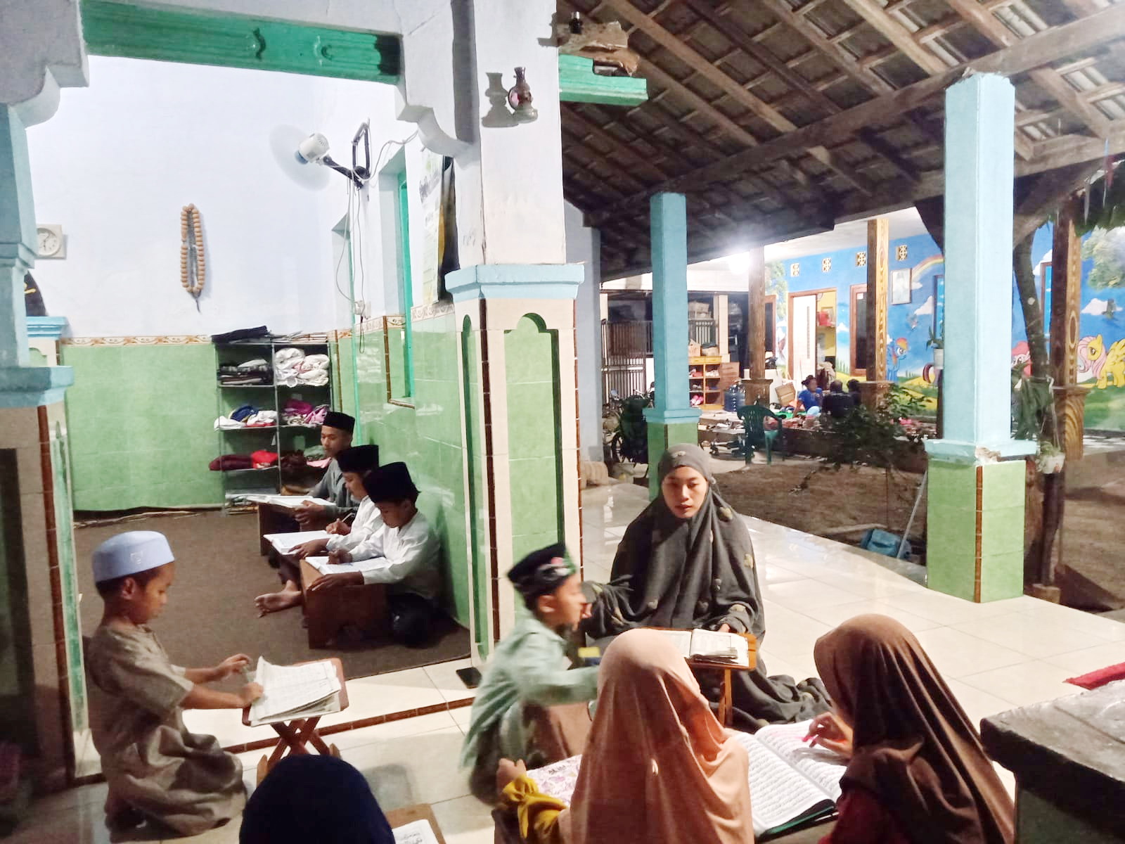 PENGABDIAN: Seorang guru ngaji Latifatul Ulfa (pakai mukena) mengajar santri di Kelurahan Mlajah, Kecamatan Bangkalan, Rabu (18/9). (IMAMUDIN/JPRM)