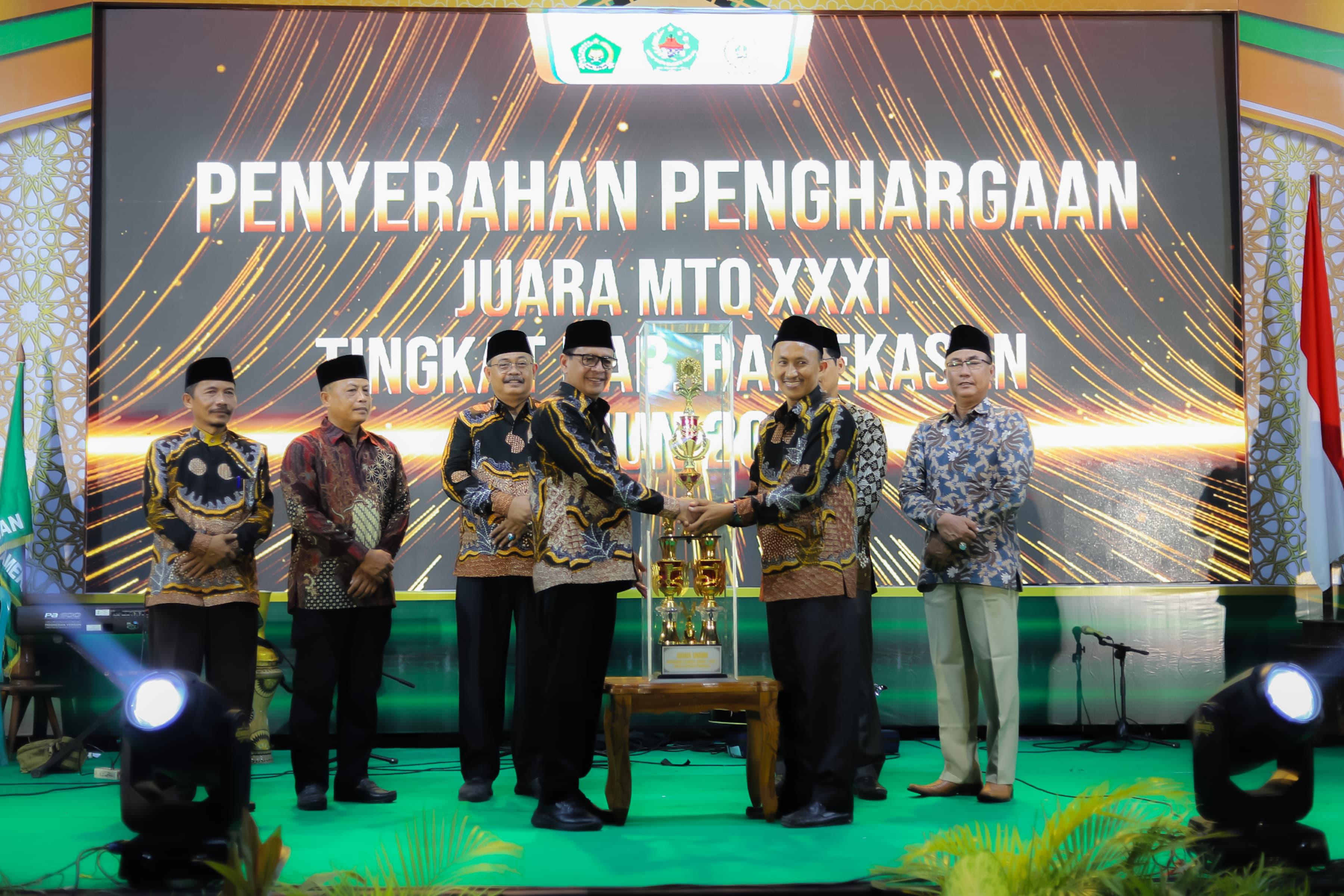 BANGGA: Pj Bupati Pamekasan Masrukin menyerahkan penghargaan juara MTQ XXXI tingkat kabupaten pada Camat Palengaan Muzanni di Lapangan Nagara Bhakti, Rabu (25/9) malam.