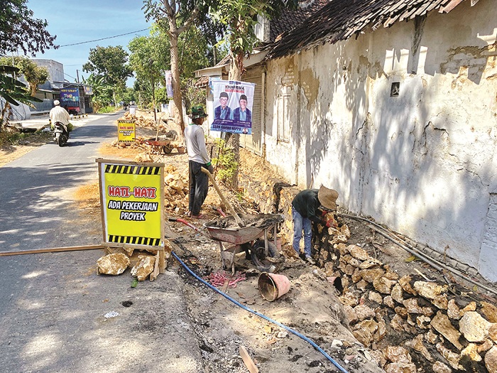 SIBUK: Pekerja yang belum mengenakan APD sedang menggarap proyek pembangunan drainase di Desa Polagan, Kecamatan Galis, Pamekasan, Rabu (2/10). (AYU LATIFAH/JPRM)