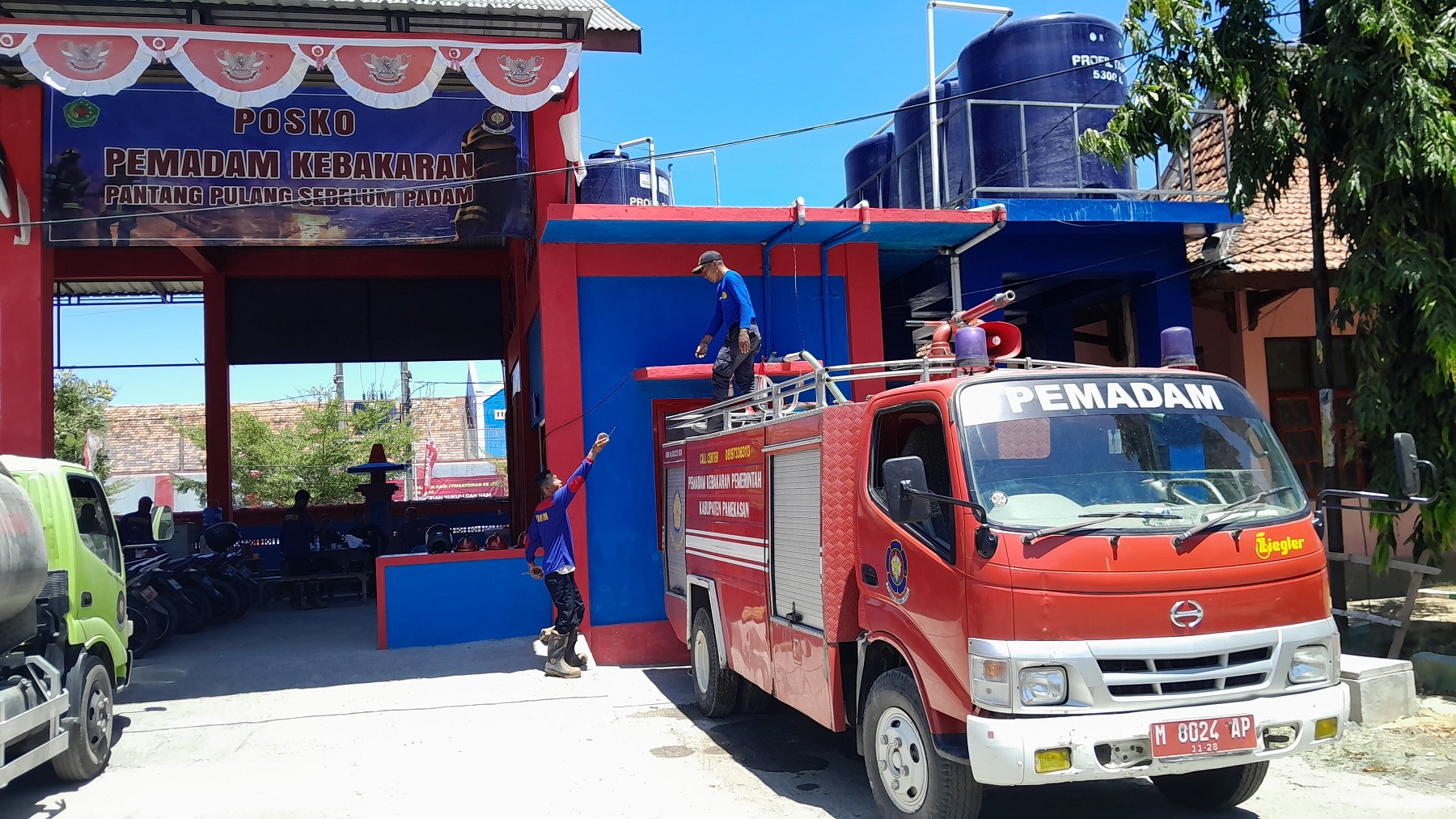 ISTIRAHAT: Tim Damkar Pamekasan mengisi ulang air mobil pemadam kebakaran.