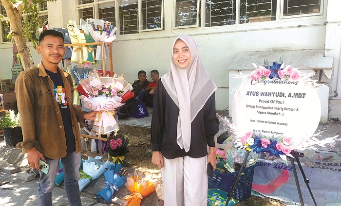 PRODUKTIF: Pemilik Dr Florist Ahmad Dahlan (kemeja cokelat) bersama tunangannya, Juhairiyah, menjaga stan di kampus Poltera, Sabtu (21/9). (JUNAIDI PONDIYANTO/JPRM)