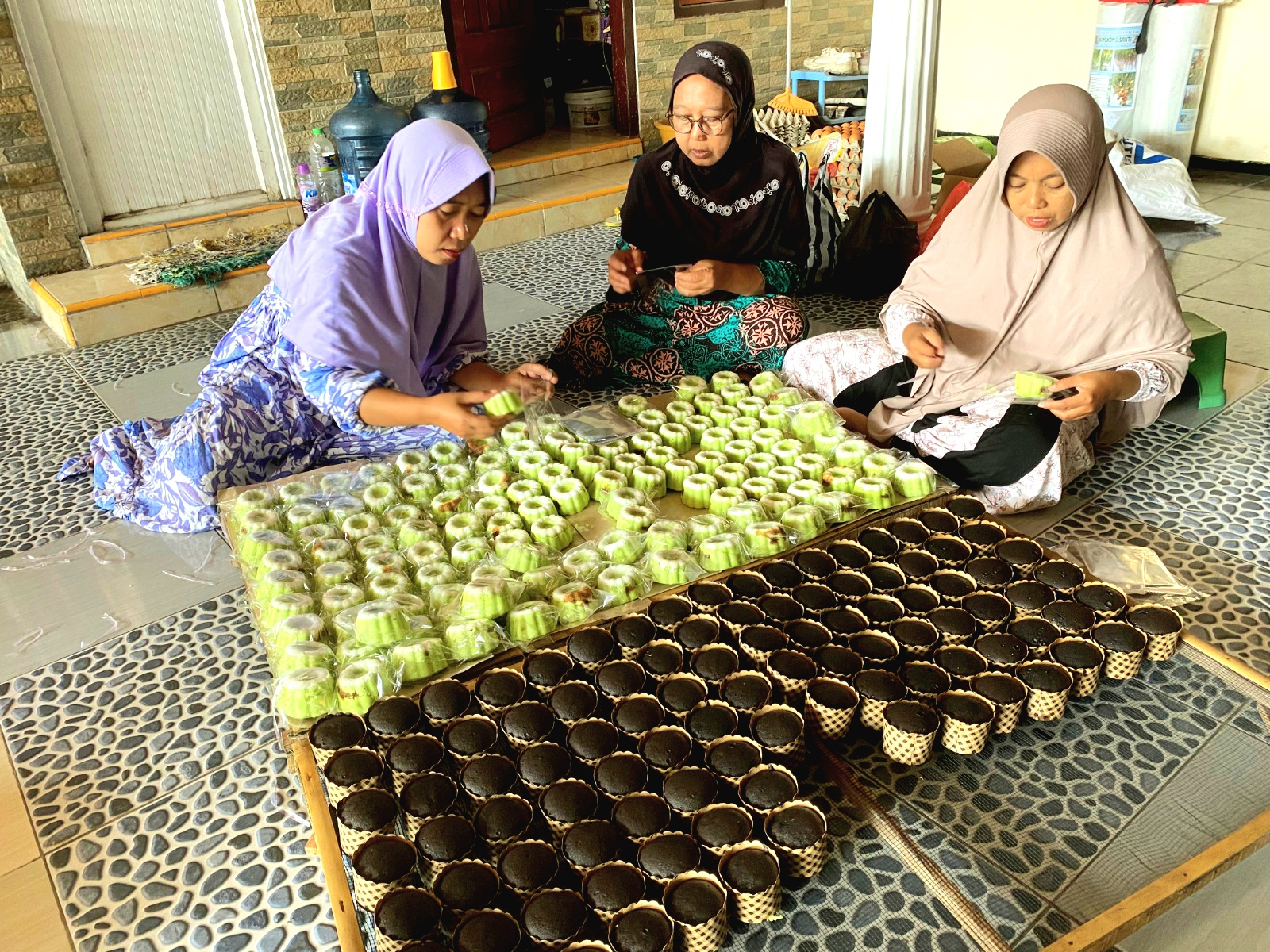 BERAGAM: Yuyun Aini (kanan) mengemas kue basah pesanan pelanggan di Dusun Talang, Desa Montok, Kecamatan Larangan, Pamekasan, Sabtu (28/9). (AYU LATIFAH/JPRM)