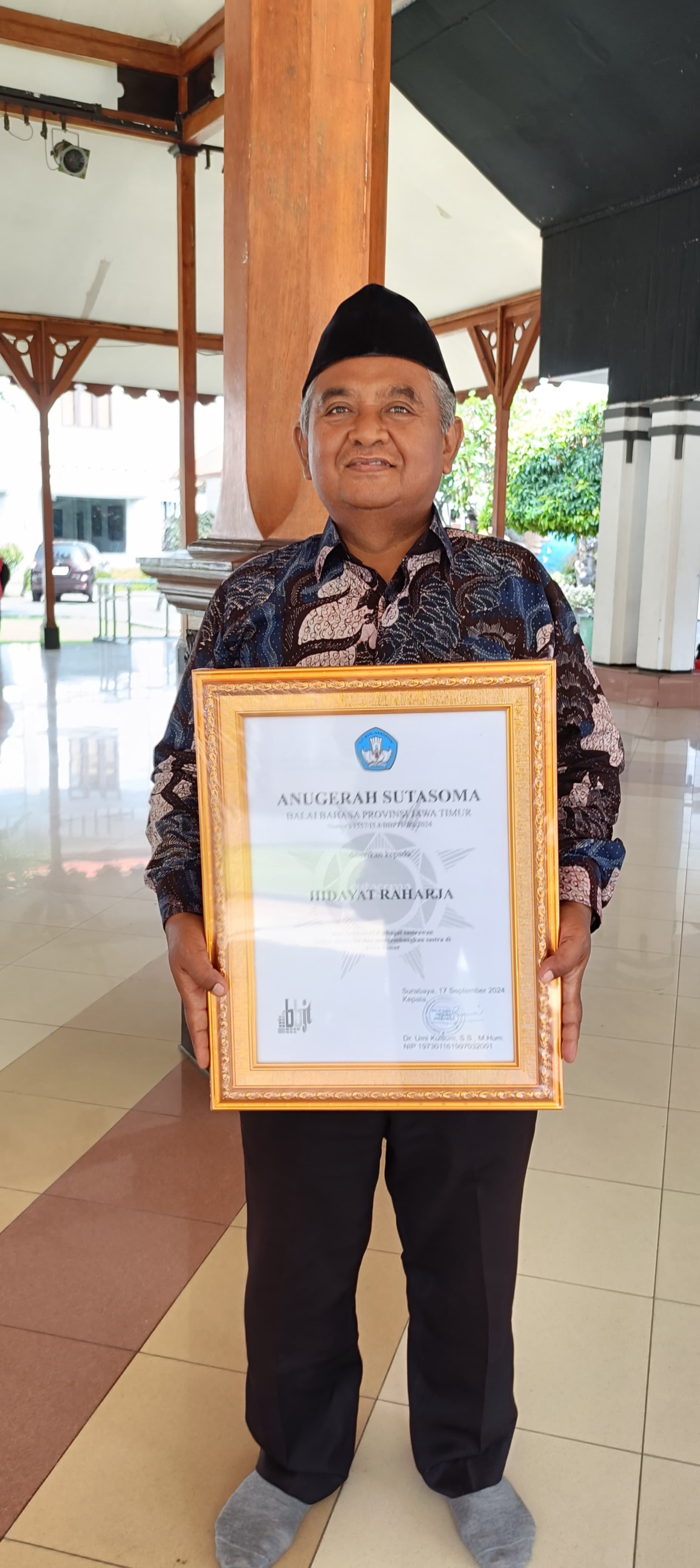 APRESIASI: Hidayat Raharja menunjukkan piagam penghargaan Anugerah Sutasoma 2024 di Pendopo Taman Budaya Cak Durasim, Kamis (17/10). (LUKMAN HAKIM AG./JPRM)