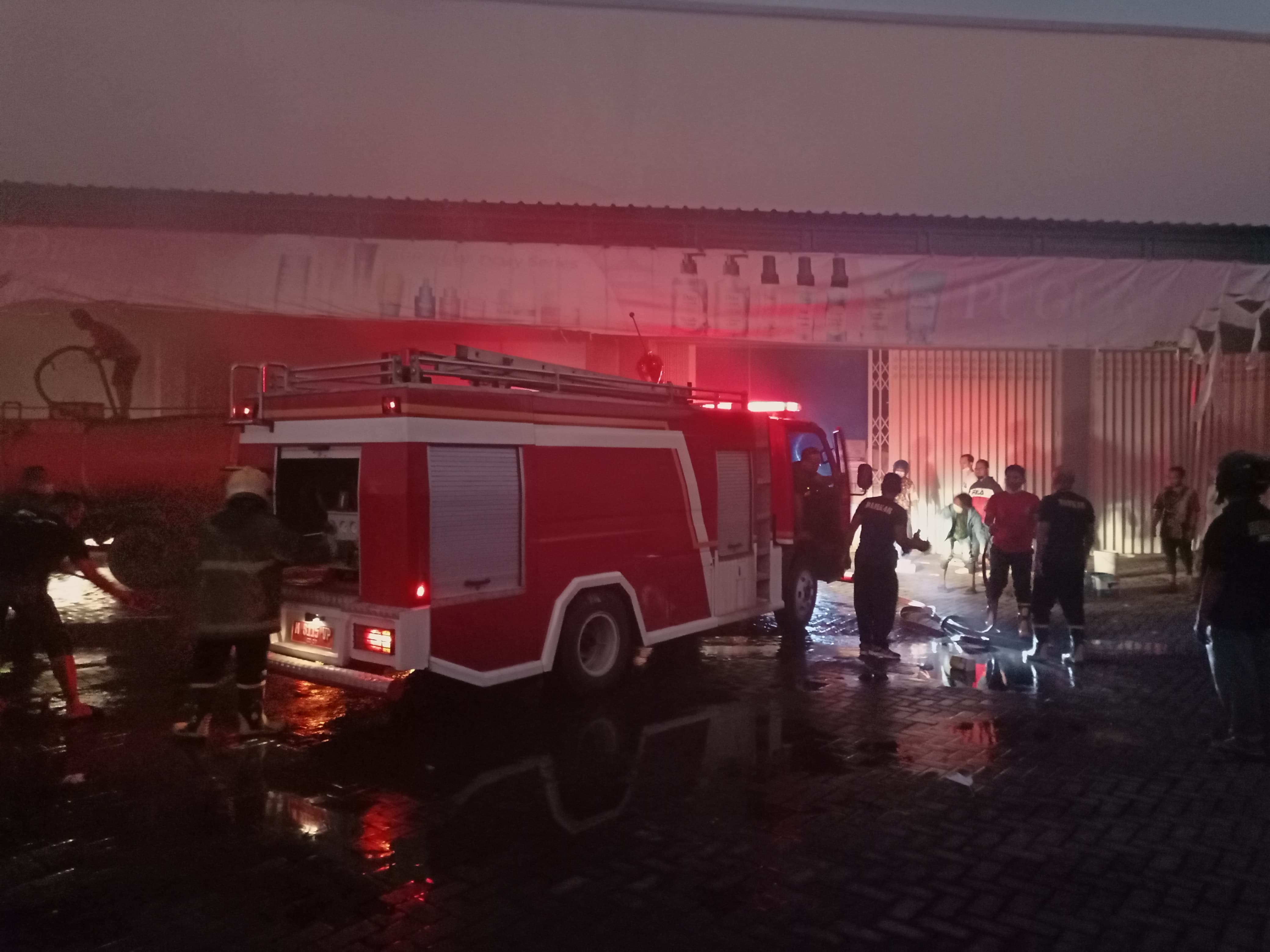 BERJIBAKU: Petugas damkar berusaha memadamkan api di Toko Puger Sumenep, Rabu (24/7). (MOH. LATIF/JPRM)