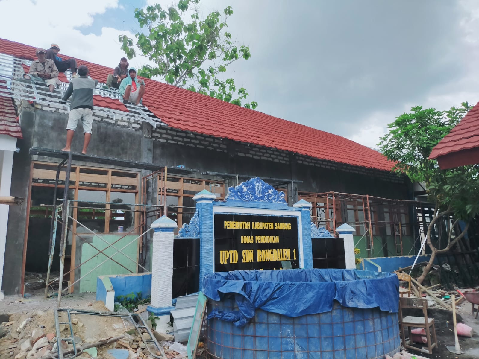 BELUM TUNTAS: Pekerja memasang atap ruang kelas sisi selatan SDN Rongdelem 1, Sampang, Rabu (23/10). (ANIS BILLAH/JPRM)