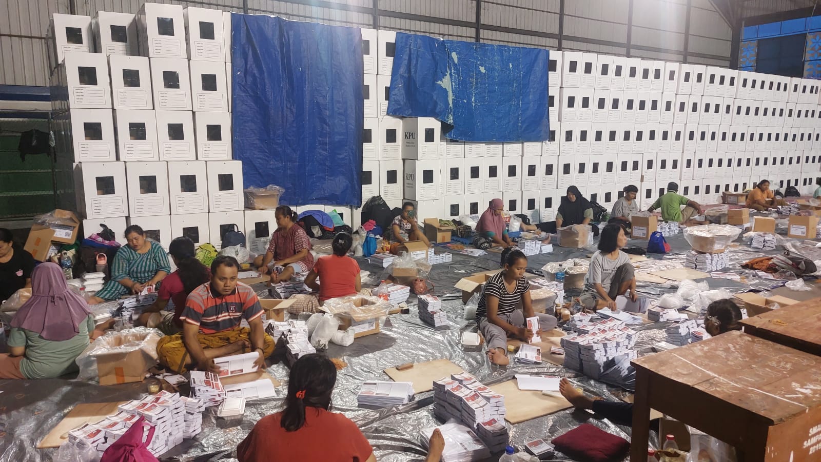 LESEHAN: Sejumlah pekerja melipat surat suara untuk pemilihan gubernur Jawa Timur di gudang logistik Indoor Sampang, Minggu (3/11) malam. (JUNAIDI PONDIYANTO/JPRM)