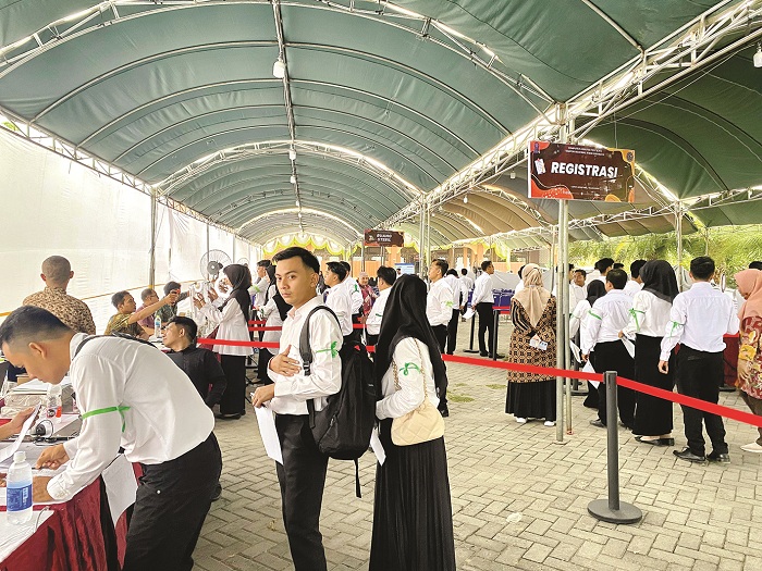 ANTRE: Peserta mengisi administrasi sebelum masuk lokasi tes CPNS di Kecamatan Tlanakan, Pamekasan, Minggu (20/10). (AYU LATIFAH/JPRM)