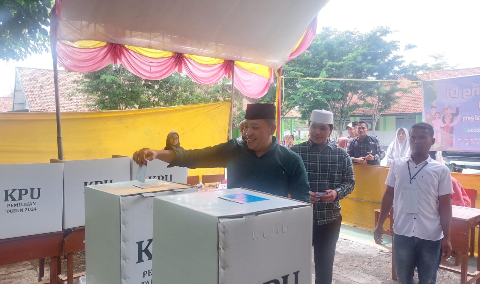 MASUK: Cabup Sampang  H. Slamet Junaidi didampingi putranya, Dafa Dzikri Januar Junaidi, memasukkan surat suara di TPS 09 Karang Dalam, Sampang, Rabu (27/11).