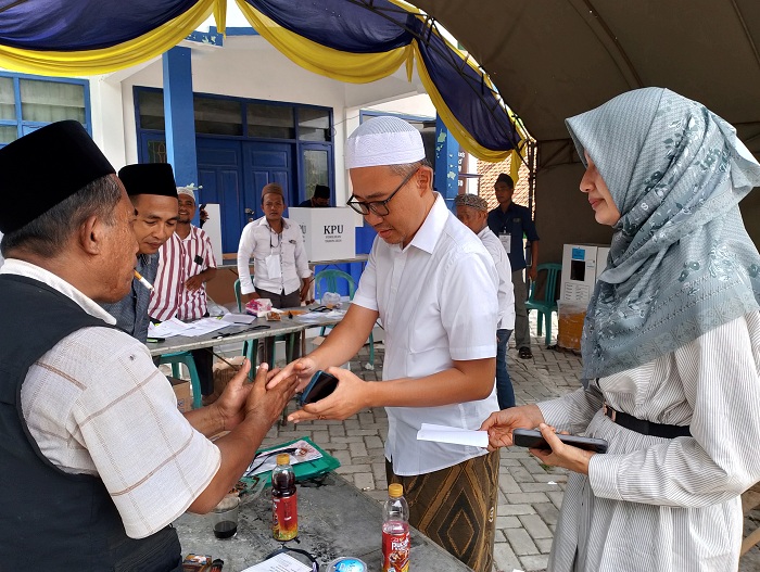 DEMOKRASI: Cabup nomor urut 1 KH Muhammad bin Muafi Zaini bersama istrinya mendatangi TPS 01 di Desa Prajjan, Kecamatan Camplong, Sampang, Rabu (27/11). (UBAIDILLAHIR RAIE/JPRM)