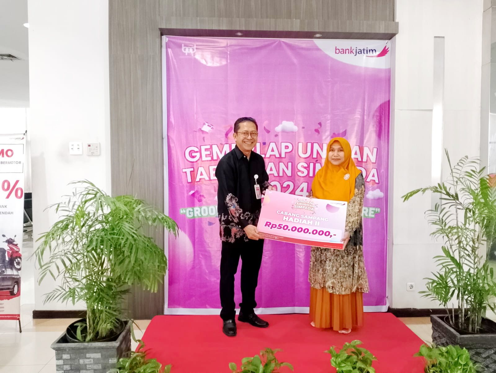 NASABAH: Pemimpin Cabang (Pimcab) Bank Jatim Sampang Didik Yanuardi memberikan hadiah pada nasabah Irma Dwi Ratna di kantornya&nbsp;Kamis (28/11). (UBAIDILLAHIR RAIE/JPRM)