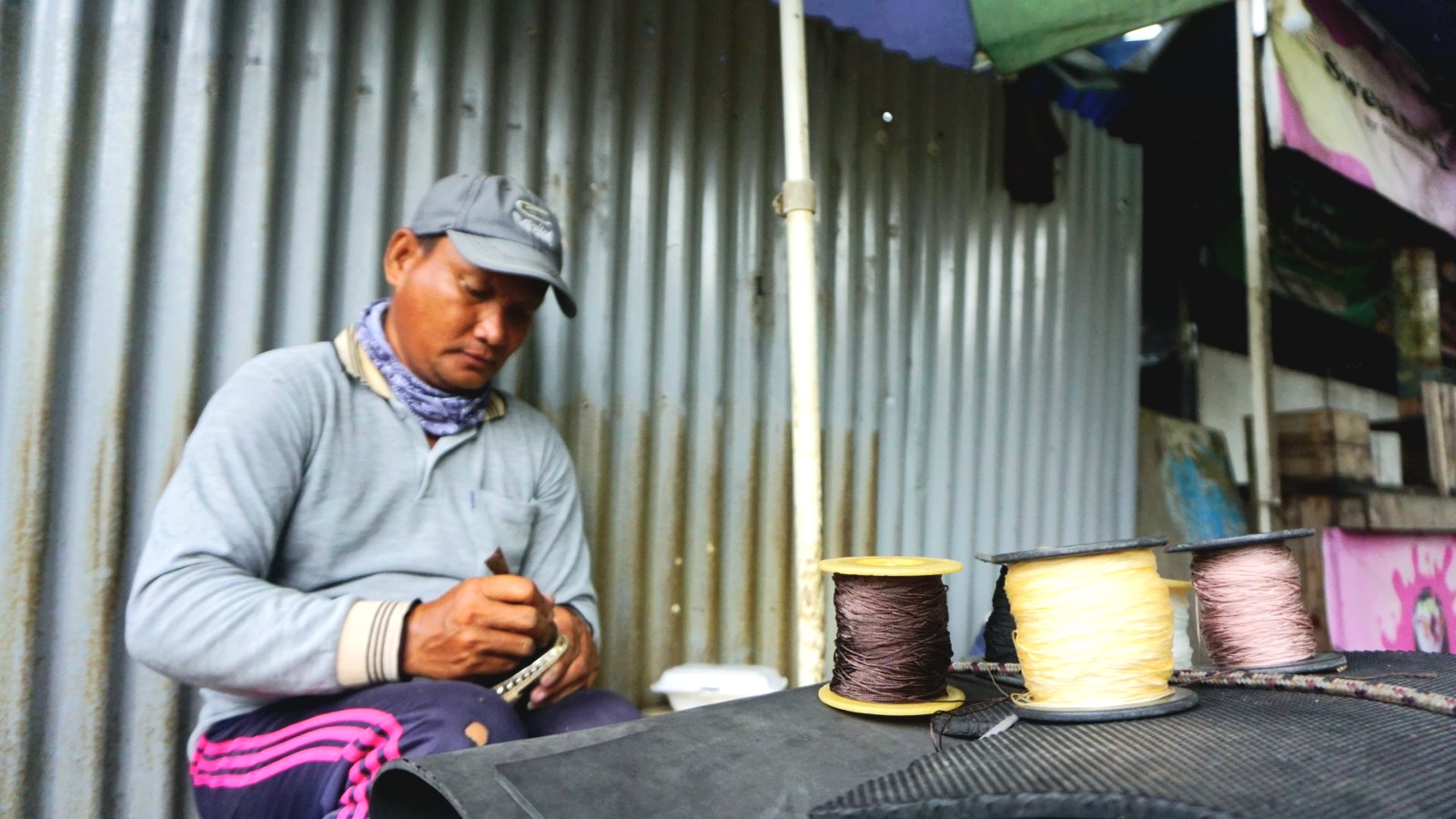 MERASA AMAN: Nursam menjahit sandal milik pelanggannya di seberang SDN Kemayoran 1, Jalan Teuku Umar, Bangkalan, Jumat (6/12). (VIVIN AGUSTIN HARTONO /JPRM)