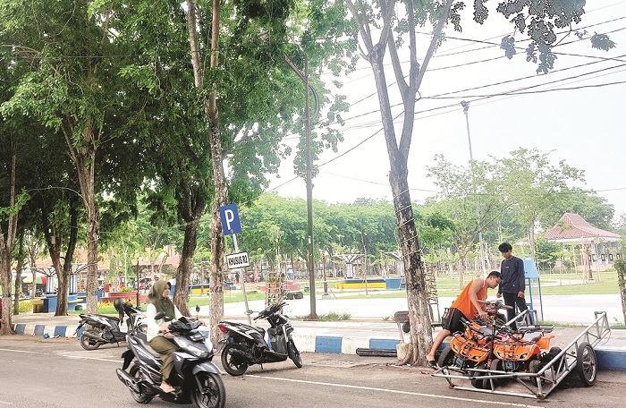 TEPI JALAN: Warga berada area titik parkir di Jalan Wijaya Kusuma, Kota Sampang, Senin (25/11). (JUNAIDI PONDIYANTO/JPRM)