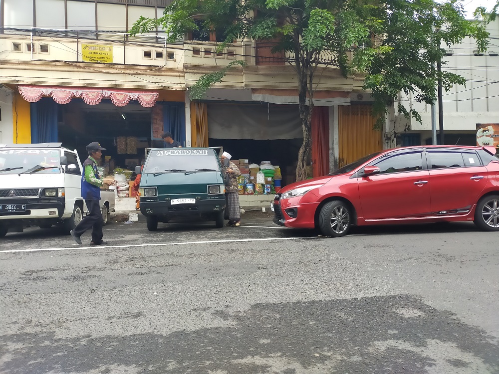 BERTUGAS: Jukir mengatur kendaraan di Jalan Panglima Sudirman, Bangkalan, Senin (16/12). (VIVIN AGUSTIN HARTONO/JPRM)