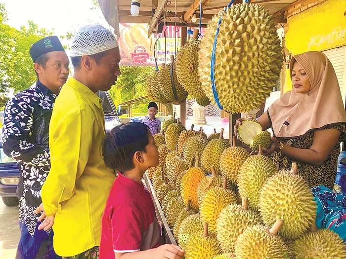DIDATANGI PENGUNJUNG: Warga membeli durian di toko milik Salamah di Jalan Raya Lebbek&ndash;Pegantenan, Pamekasan, Jumat (27/12). (MOH. IQBAL AFGANI/JPRM)