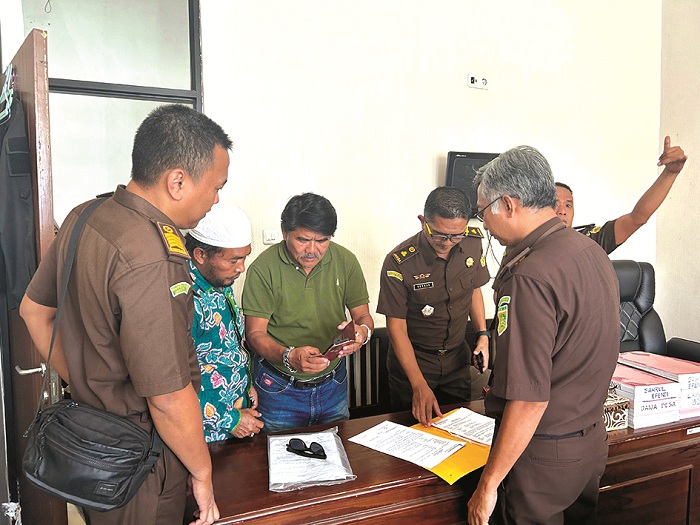 SERIUS: Pengacara Zamahsyari, Hornaidi (kaus hijau), bersama keluarga Zamahsyari memeriksa berkas seusai menyerahkan titipan uang di kantor Kejari Pamekasan, Senin (30/12/2024).