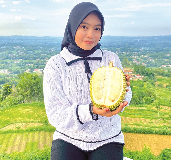 CIRI KHAS: Nur Lailatul Qudriyah memegang durian di Wisata Puncak Ratu Pamekasan, Jumat (3/1). (MOH. IQBAL AFGANI/JPRM)
