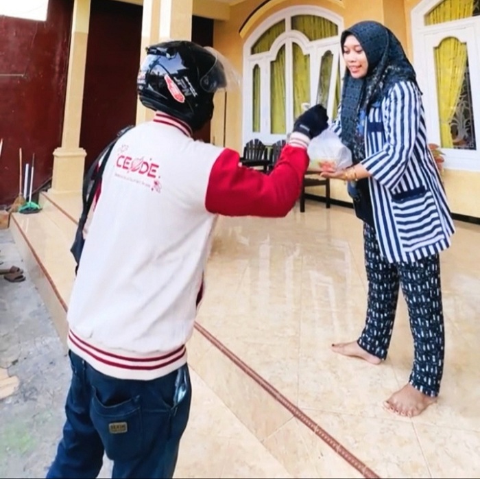KREATIF: Pemilik Dapur Sin-Sin Sumenep Sinta Amelia menyerahkan pesanan kepada kurir untuk diantarkan ke pelanggan dari rumahnya di Desa Kolor, Kecamatan Kota Sumenep, Sabtu (28/12/2024).