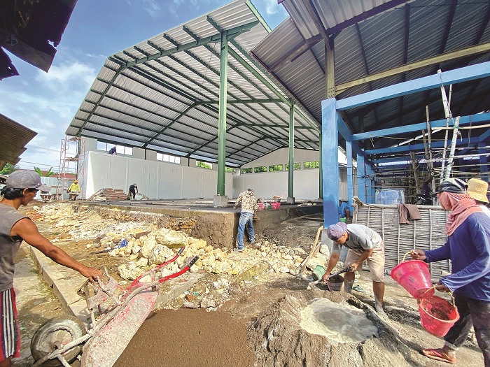 TAK TUNTAS: Pekerja proyek pembangunan revitalisasi Pasar Keppo, Kecamatan Galis, Pamekasan, mengaduk semen Rabu (8/1). (AYU LATIFAH/JPRM)