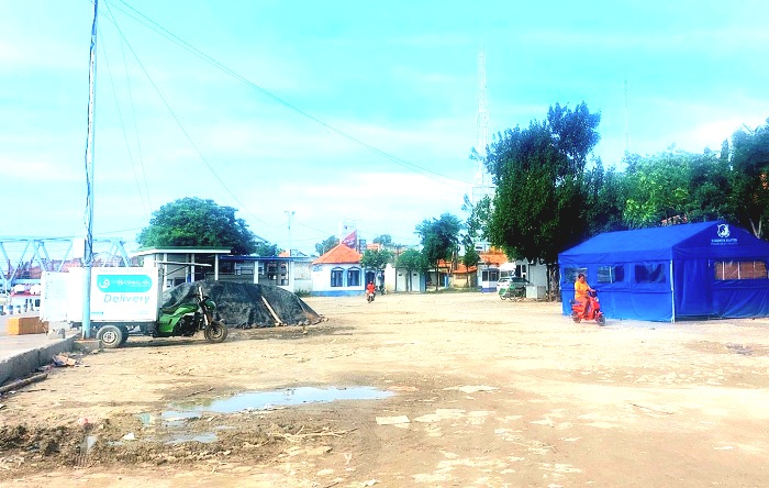 BUTUH PERBAIKAN: Warga melintas di sekitar area yang becek di Pelabuhan Tanglok, Kota Sampang, Kamis (9/1). (JUNAIDI PONDIYANTO/JPRM)