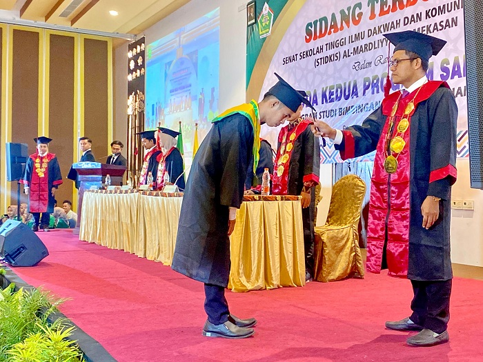 DIKUKUHKAN: Ketua STIDKIS Al-Mardliyyah Pamekasan Yanto, S.Pd.I., M.A. memindahkan tali toga wisudawan, Rabu (15/1). (MOH. IQBAL AFGANI/JPRM)