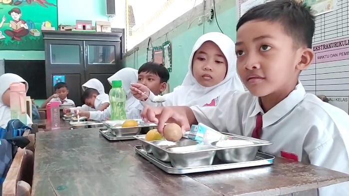 PEMENUHAN GIZI: Siswa menikmati menu makan siang gratis di SDN Pandian 1, Kecamatan Kota Sumenep, Senin (13/1). (MOH. LATIF/JPRM)