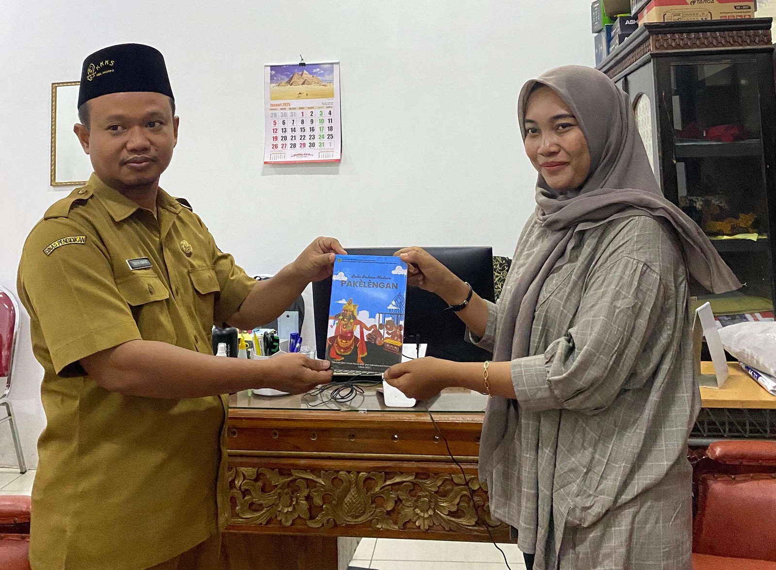 MENGINSPIRASI: Kabid Pembinaan SD Dispendikbud Pamekasan Taufik Hidayat menyerahkan sebuah buku saat ditemui jurnalis JPRM di kantornya Selasa (14/1). (DOKUMEN JPRM)