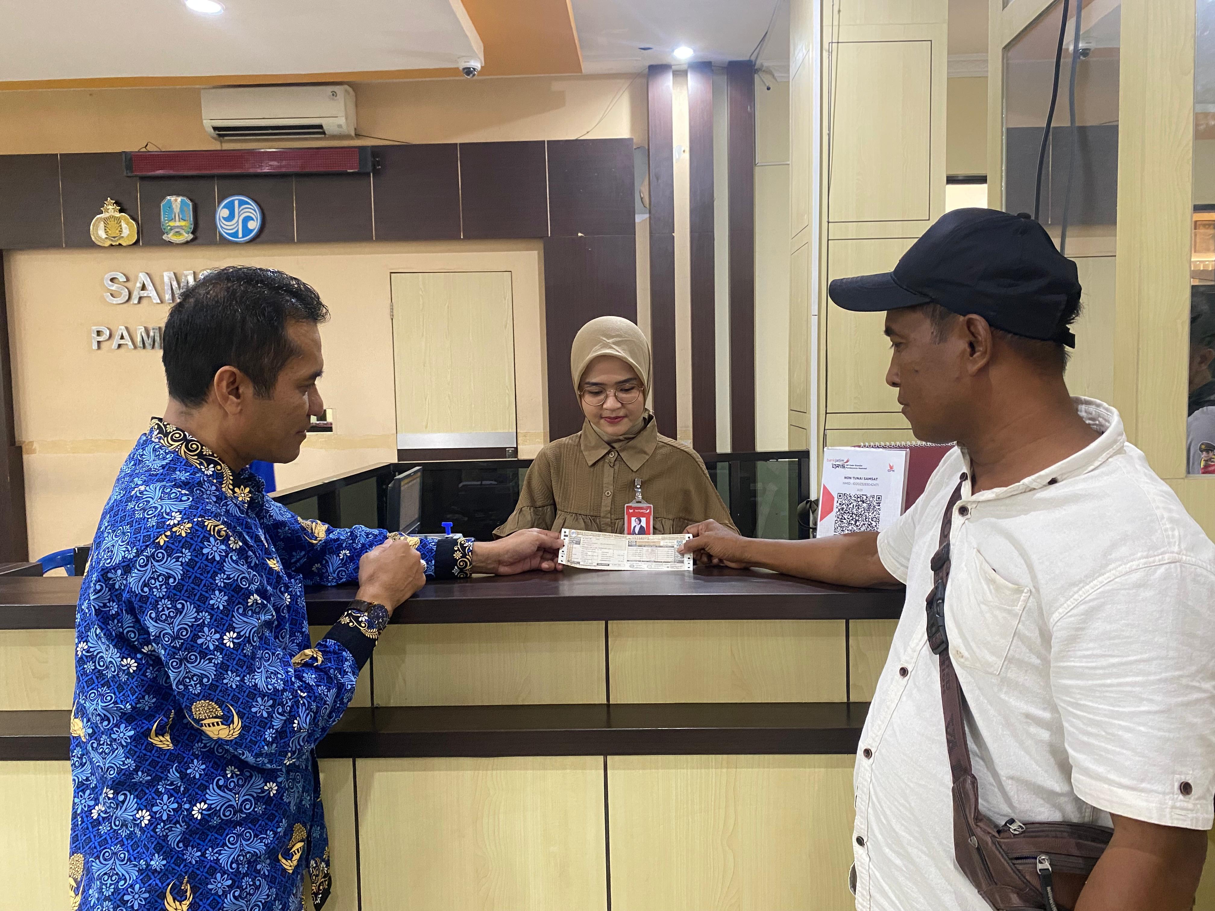 AMATI PELAYANAN: Warga menyerahkan STNK dibantu PDPP Samsat Pamekasan Abdur Rakhman (kiri) kemarin. (MOH. IQBAL AFGANI/JPRM)