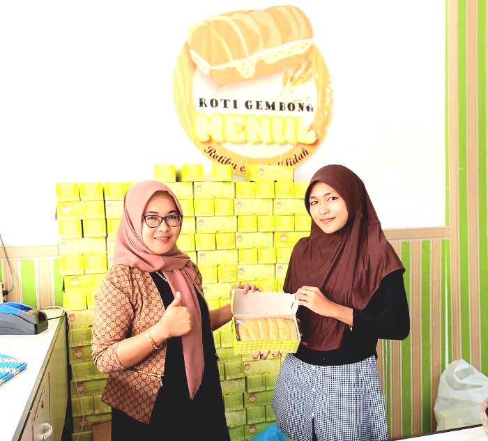 DISUKAI PELANGGAN: Pemilik usaha Roti Gembong Menul Ramadani (kiri) dan kasir Elma menunjukkan roti dalam kotak sebelum diboyong pembeli di outlet Kalianget, Sumenep, Jumat (17/1).