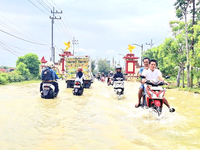 BUTUH PENANGANAN: Sejumlah pengendara menerobos banjir di jalan nasional Desa Patean, Kecamatan Batuan, Sumenep, Rabu (22/1). (MOH. LATIF/JPRM)