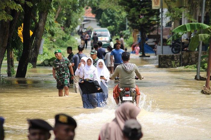 TERDAMPAK BANJIR: Warga menerobos air banjir di Kecamatan Arosbaya, Bangkalan, Selasa (21/1). (VIVIN AGUSTIN HARTONO/JPRM)
