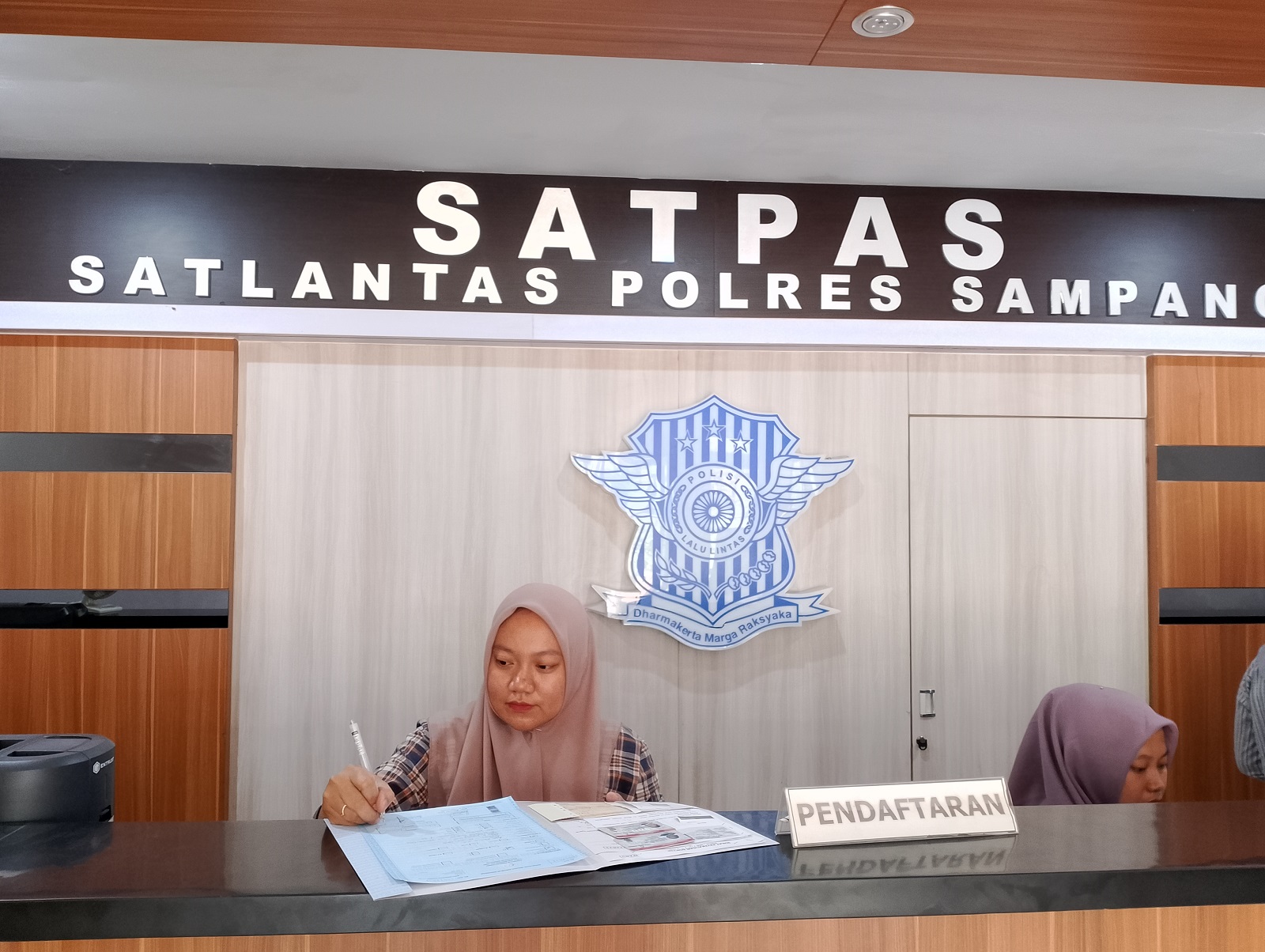 SIBUK: Petugas Satpas SIM Polres Sampang tengah bertugas di loket pendaftaran SIM Satlantas Polres Sampang Jumat (24/1). (UBAIDILLAHIR RAIE/JPRM)