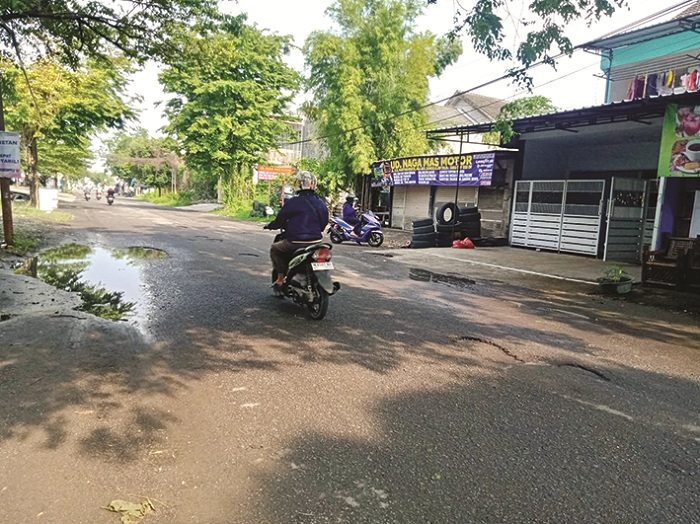 BUTUH PERBAIKAN: Pengendara melintas di sekitar jalan yang berlubang di Jalan RE Martadinata, Bangkalan, Sabtu (25/1). (IMAMUDIN/JPRM)