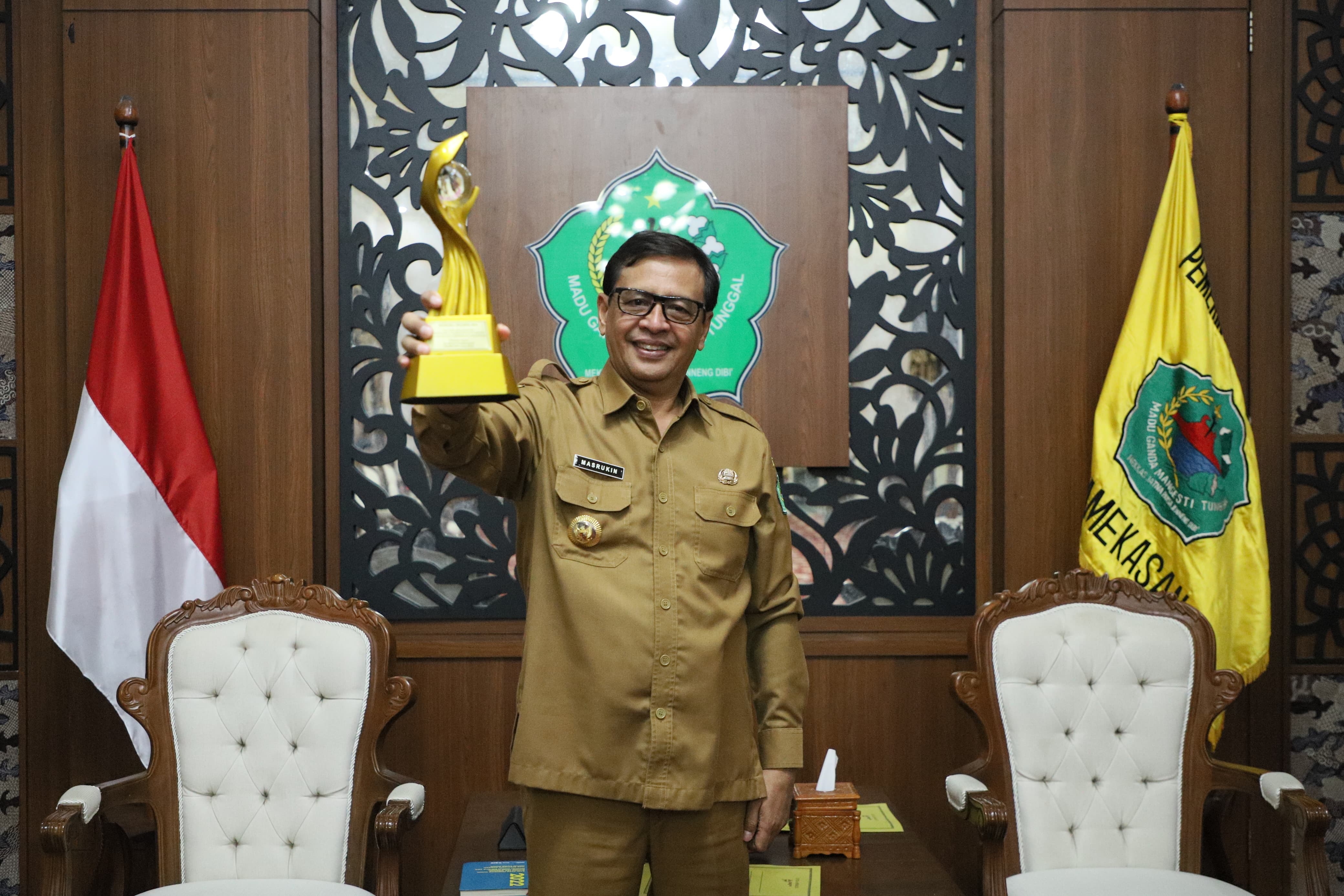 BANGGA: Pj Bupati Pamekasan Masrukin menunjukkan piala MA 2024 di Peringgitan Dalam Mandhapa Agung Ronggosukowati, Selasa, 31 Desember 2024.