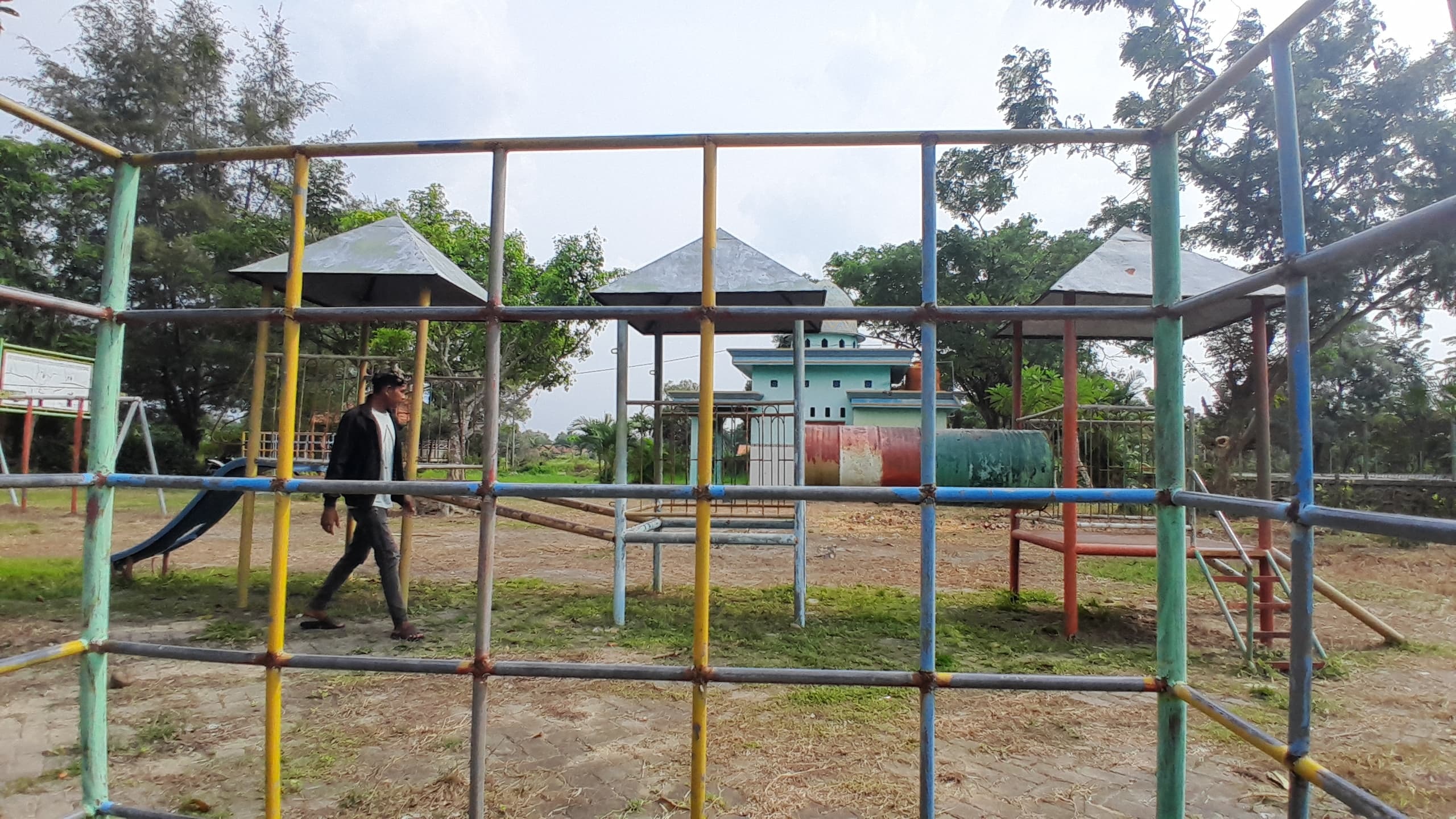 TERBENGKALAI: Warga berjalan di area Taman Asri Kowel, Pamekasan, Minggu (9/2). (M. KHOLIL RAMLI/JPRM)