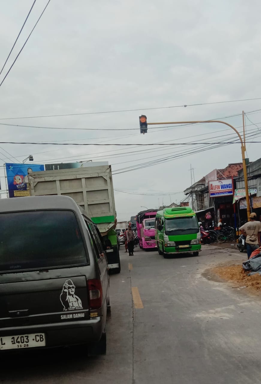 MACET : Polisi melakukan pengawalan kendaraan yang terjebak macet di Pasar Blega, Bangkalan, Senin (10/2). (JAKFAR UNTUK JPRM)