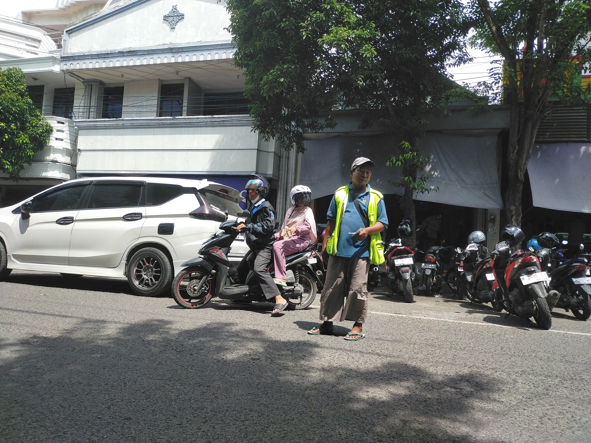 TERIK: Jukir tengah mengawal pengendara sepeda motor di Jalan Panglima Sudirman, Bangkalan, kemarin. (VIVIN AGUSTIN HARTONO/JPRM)