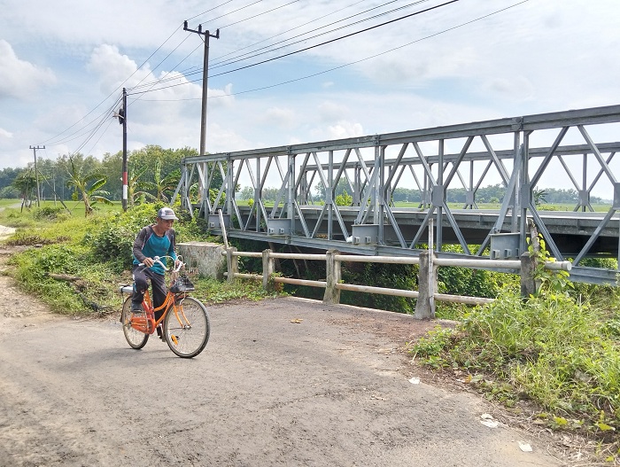 BELUM DIPERBAIKI: Warga melintas di jembatan sementara yang dipasang di Desa Meddelan, Kecamatan Lenteng, Sabtu (15/2). (MOH. IQBAL/JPRM)