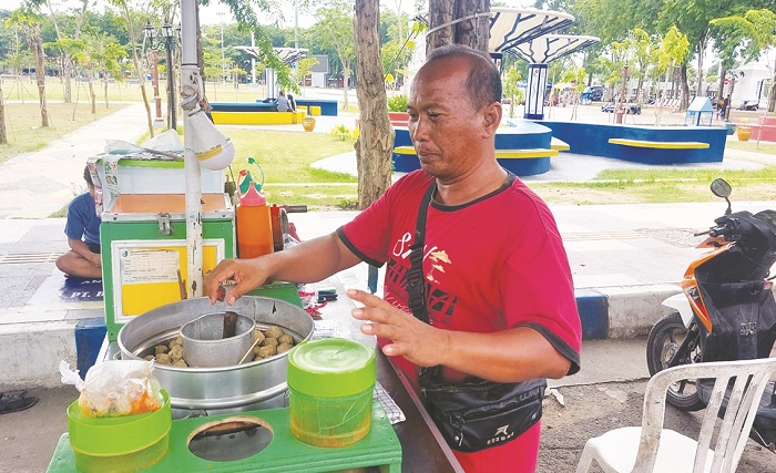 USAHA KECIL: Mohammad Saleh menyiapkan produk saat berjualan di Jalan Wijaya Kusuma, Kota Sampang, Selasa (28/1). (JUNAIDI PONDIYANTO/JPRM)
