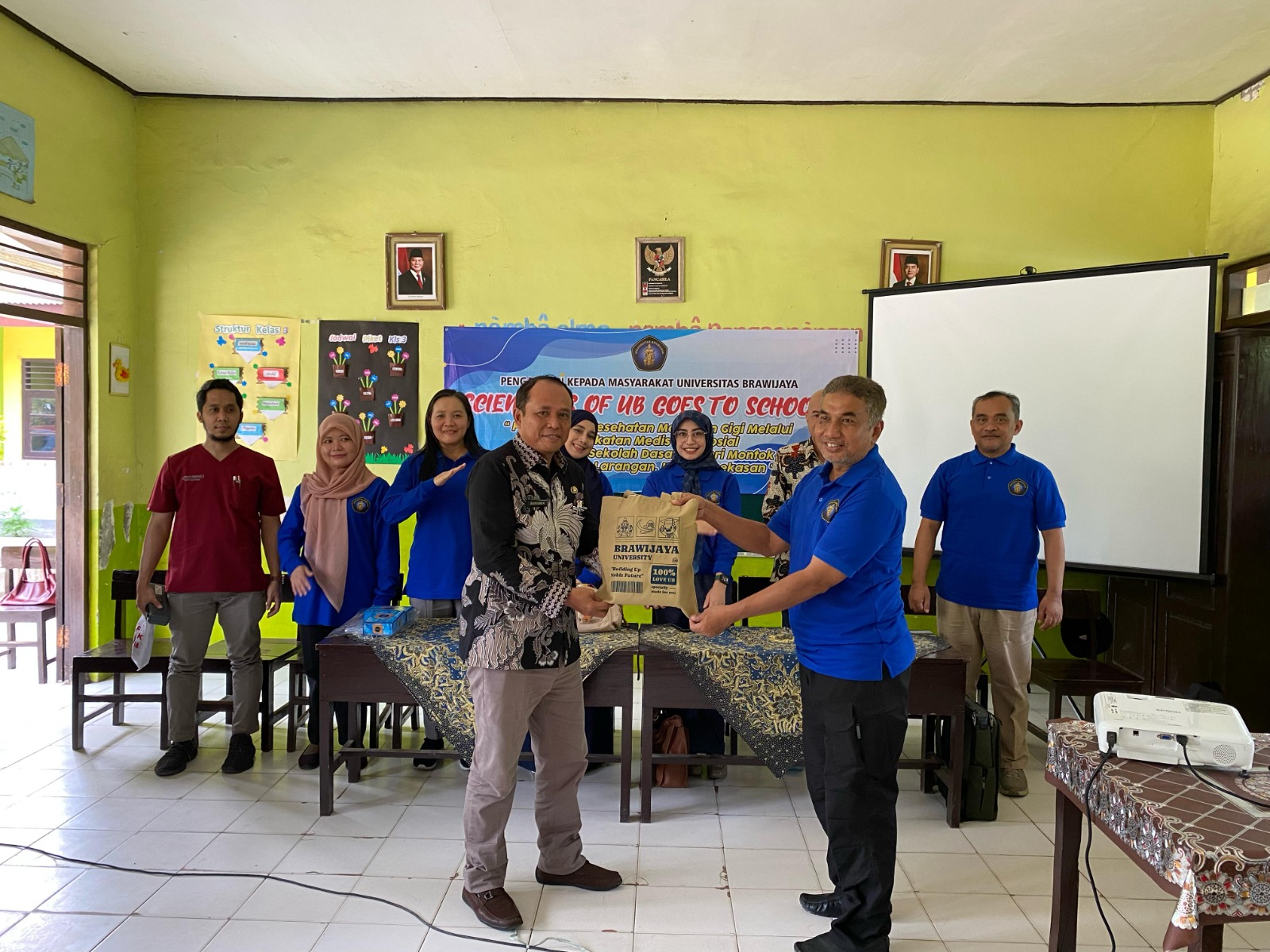 DEDIKASI: Dr. Mohammad Nuh., S.IP., M.Si (kaos dongker) memberikan cinderamata ke Kepala SDN Montok 1, Kecamatan Larangan, Pamekasan, Jumat (21/2).