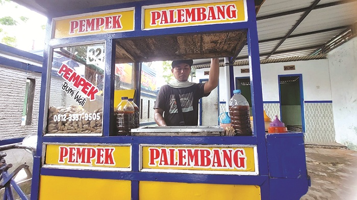 PENGHASILAN UTAMA: Penjual pempek khas Palembang Suhartono berjualan di pekarangan SDN Karang Dalem 1, Kota Sampang, Kamis (20/2). (JUNAIDI PONDIYANTOJPRM)