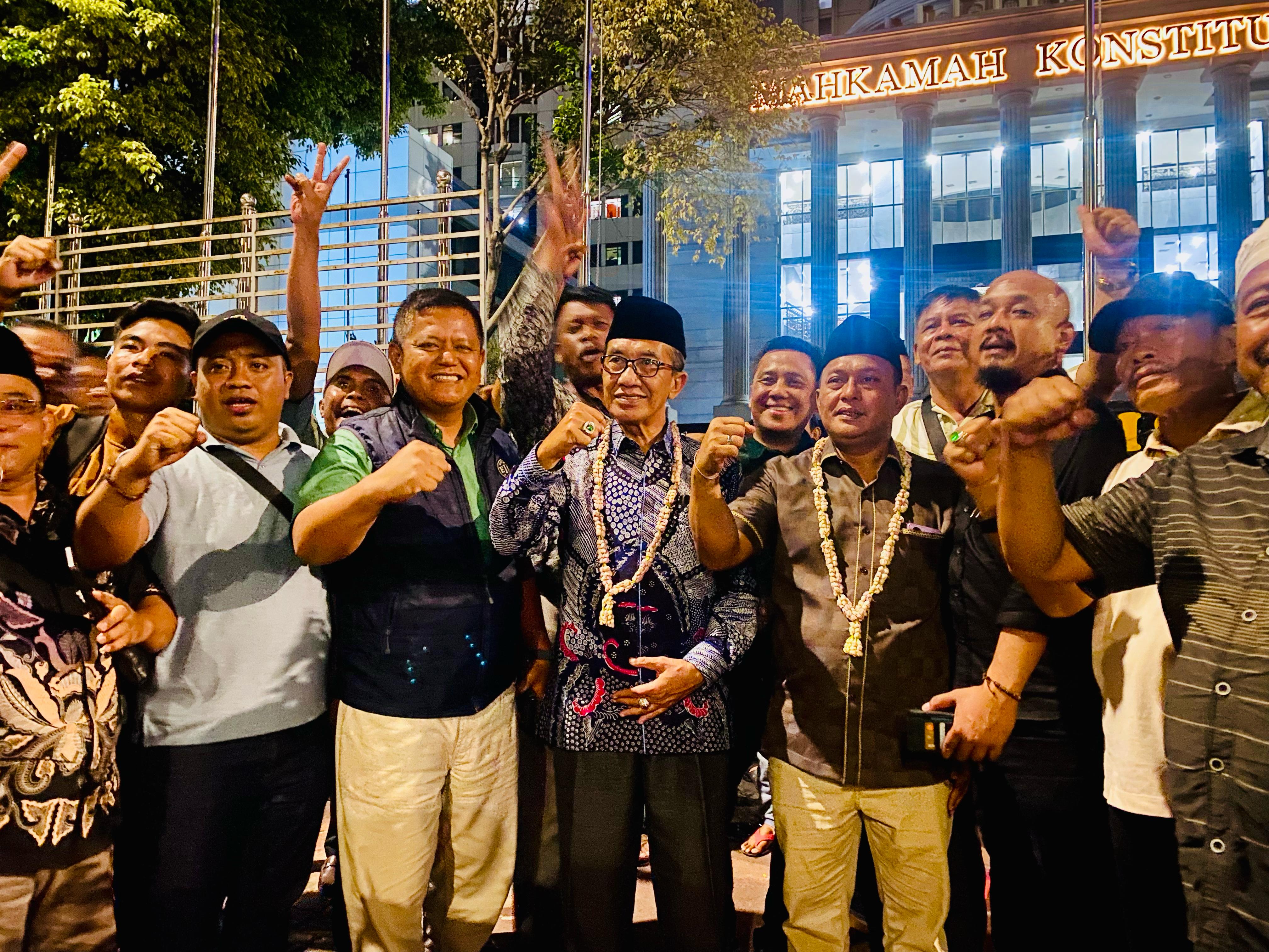 BAHAGIA: KH. Kholilurrahman dan Sukriyanto (berkalung bunga) berfoto bersama di depan Gedung MK, Senin (24/2) malam. (KHARISMA UNTUK JPRM)