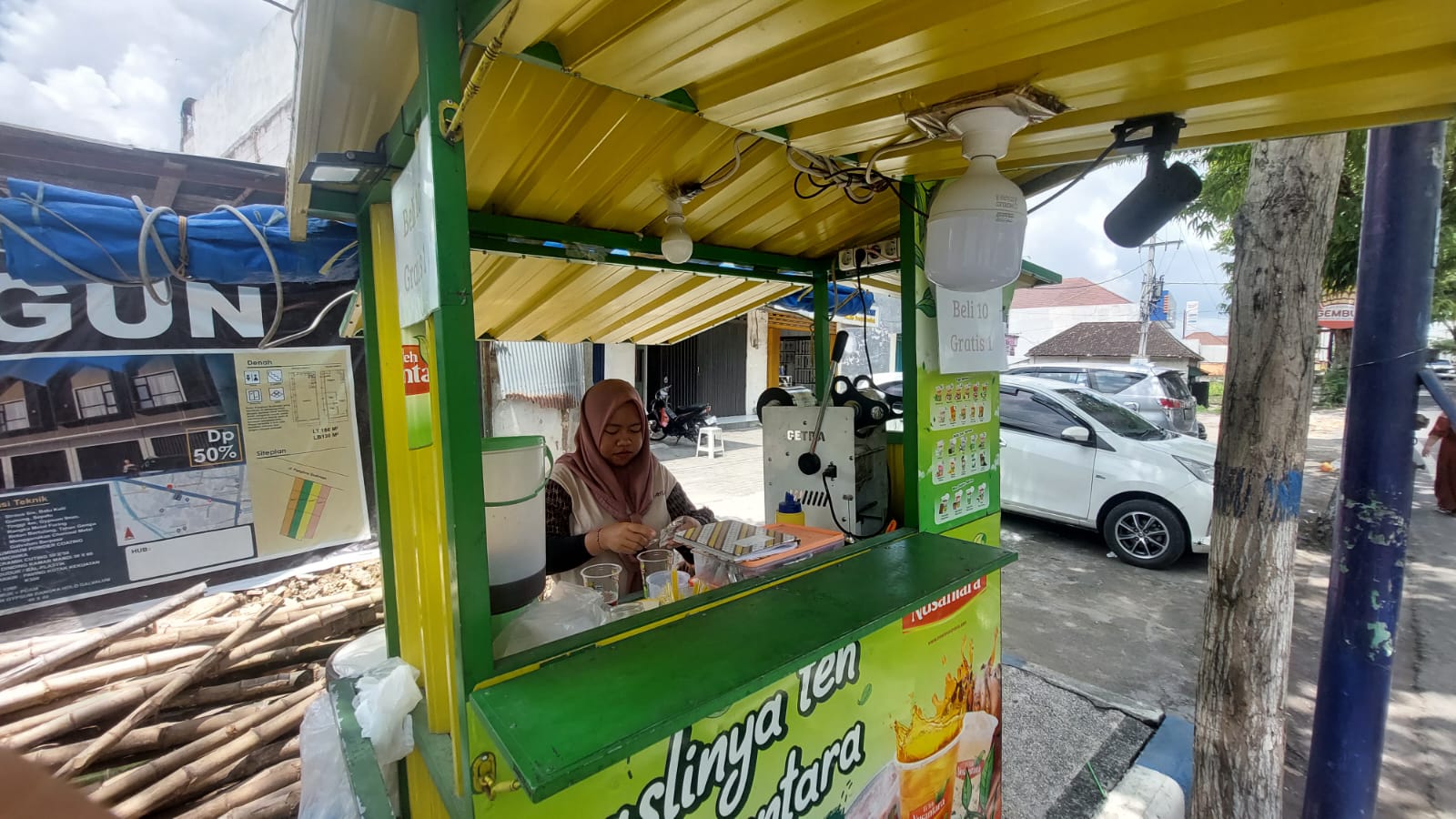 SUMBER PENGHASILAN: Penjual es teh saat menjaga lapaknya di Jalan Panglima Sudirman, Sampang, Sabtu (15/2). (JUNAIDI PONDIYANTO/JPRM)