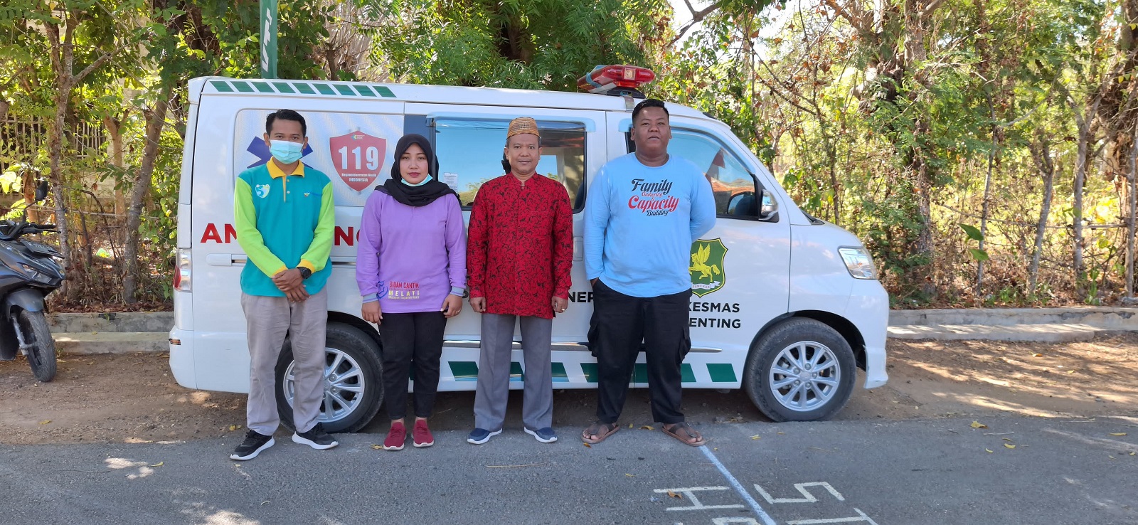 SIAP MELAYANI: Kepala Puskesmas Gili Genting Idris, S.Kep., Ns (baju batik) bersama para nakes berfoto di depan mobil pusling. (PUSKESMAS GILI GENTING UNTUK JPRM)