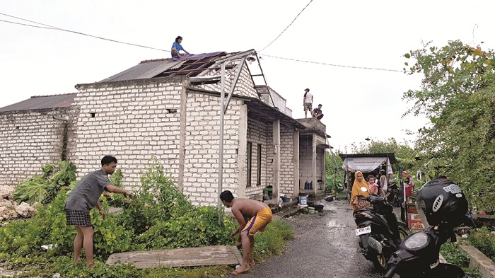 GERIMIS: Warga membantu memperbaiki salah satu atap rumah yang rusak akibat angin puyuh di Kelurahan Kraton, Bangkalan, Rabu (19/3). (IMAMUDIN/JPRM)
