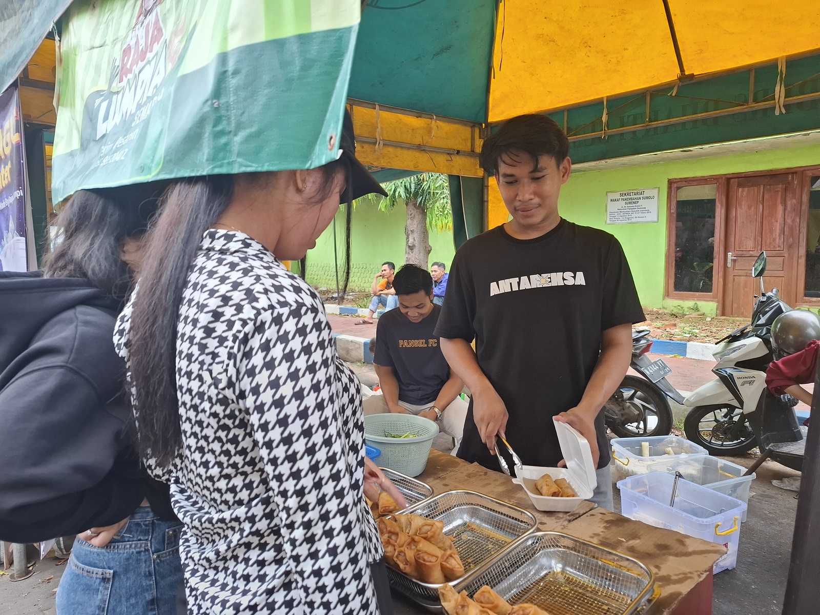 BANTU PELAKU UMKM: Ardiansyah melayani pembeli di Festival Bazar Takjil Ramadan di Jalan dr Soetomo, Kelurahan Pajagalan, Kecamatan Kota Sumenep, Rabu (19/3). (MOH. LATIF/JPRM)