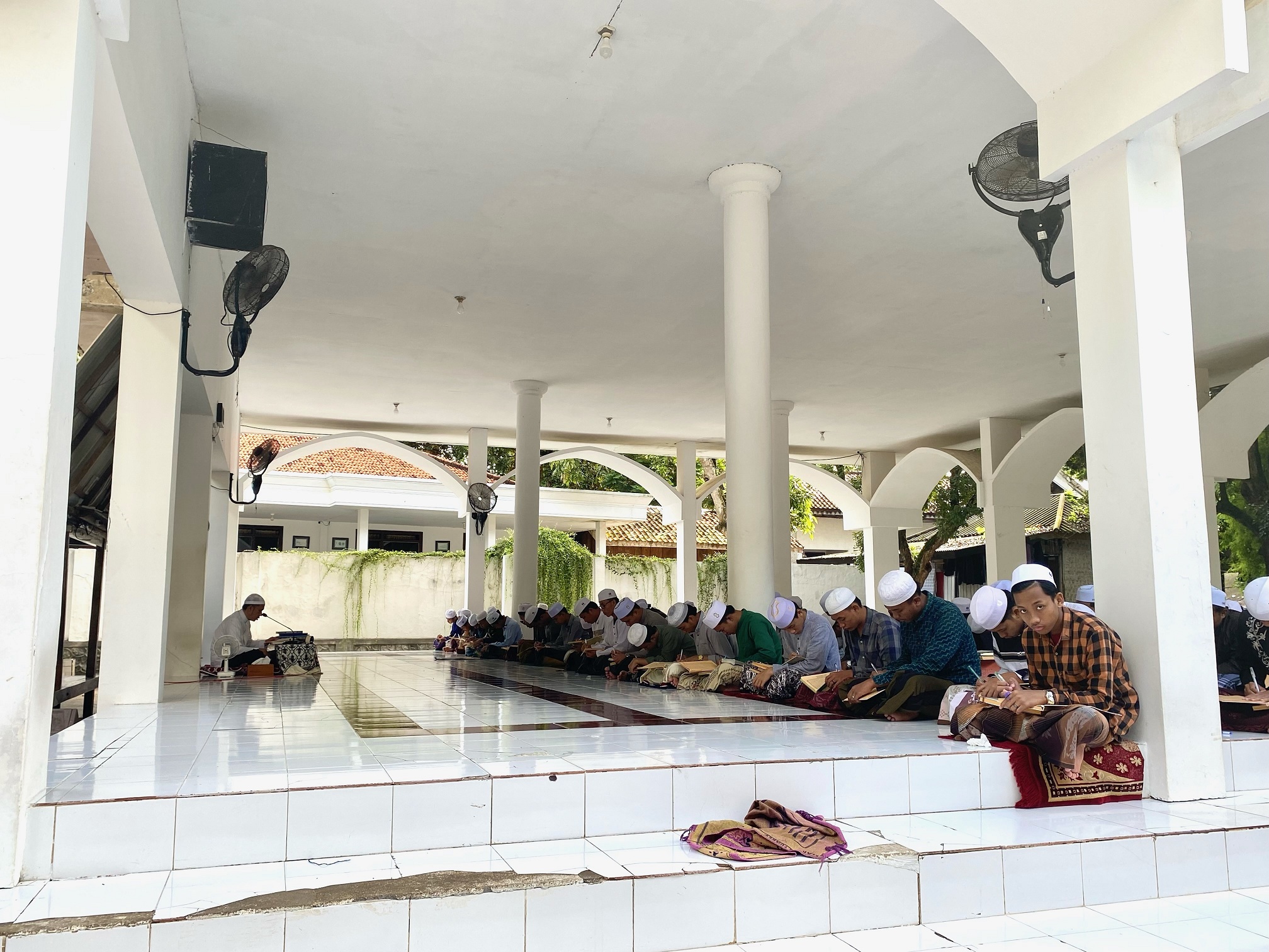 TELATEN: KH Abdul Hakam Masduqi saat membimbing santrinya mengaji kitab kuning di Masjid Ponpes Cendana Mubarok, Kadur, Pamekasan, Minggu (9/3). (AYU LATIFAH/JPRM)