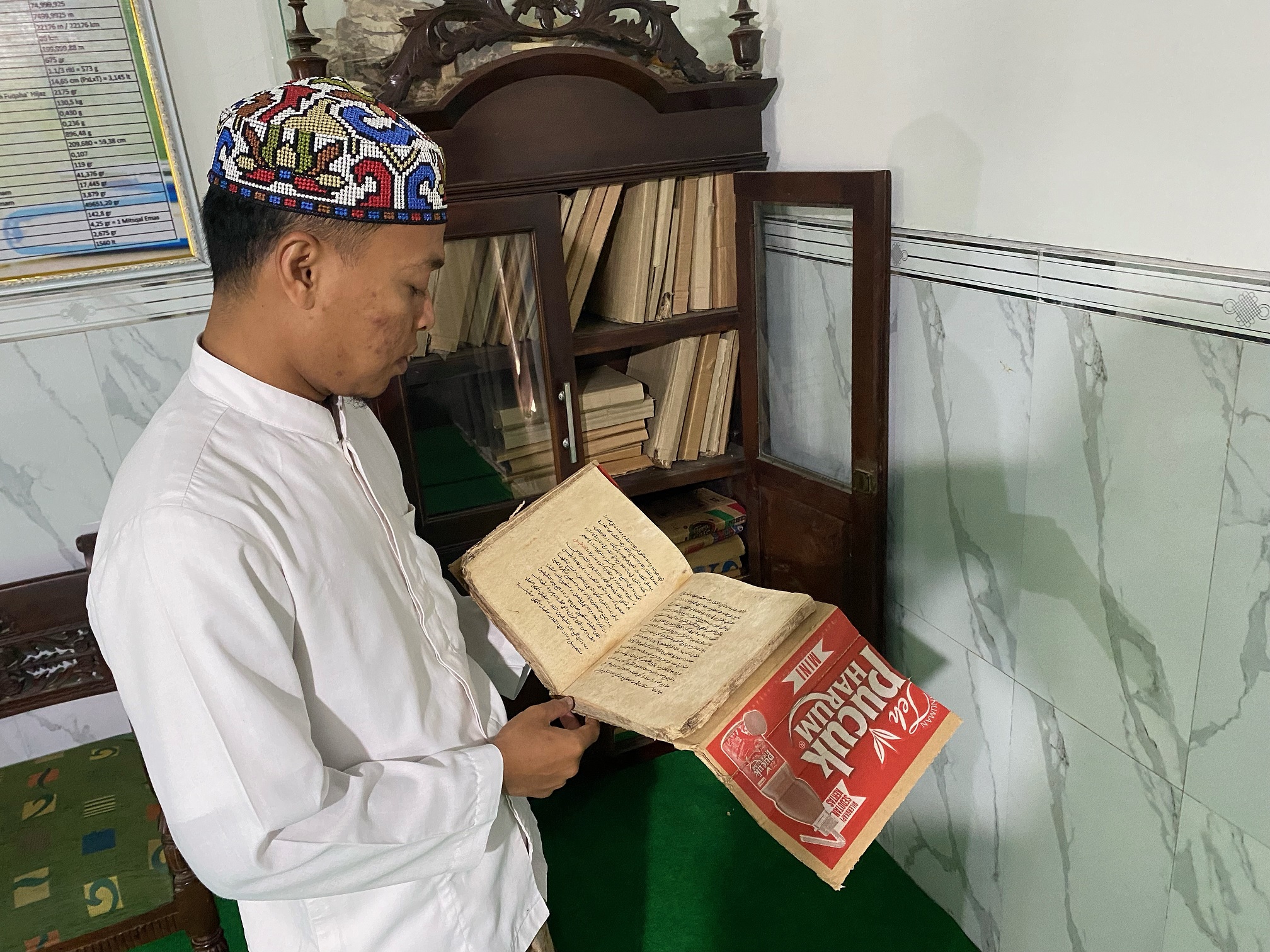 BERSEJARAH: Shohibul Bilal menunjukkan sejumlah manuskrip di Perpustakaan Ponpes Cendana Mubarok, Kadur, Pamekasan, Minggu (9/3). (AYU LATIFAH/JPRM)