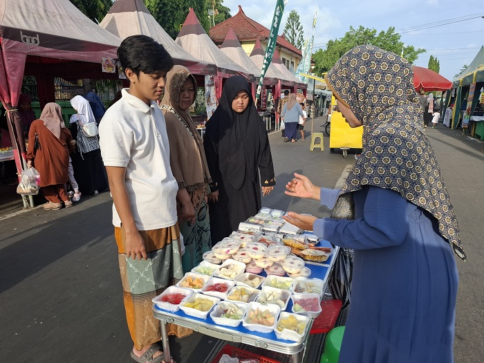 MELAYANI: Anitriana melayani pengunjung Festival Bazar Takjil Ramadan di Jalan dr Soetomo, Kelurahan Pajagalan, Kecamatan Kota Sumenep, Kamis (27/3). (MOH. LATIF/JPRM)