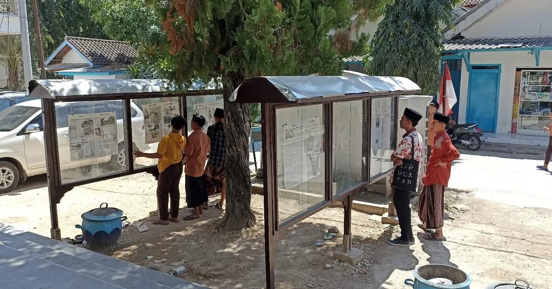 CINTA BACA: Santri Pondok Pesantren Annuqayah membaca koran Jawa Pos dan Jawa Pos Radar Madura di depan posko daerah Latee, Minggu, 30 Juli 2023. (LUKMAN HAKIM AG/JPRM)