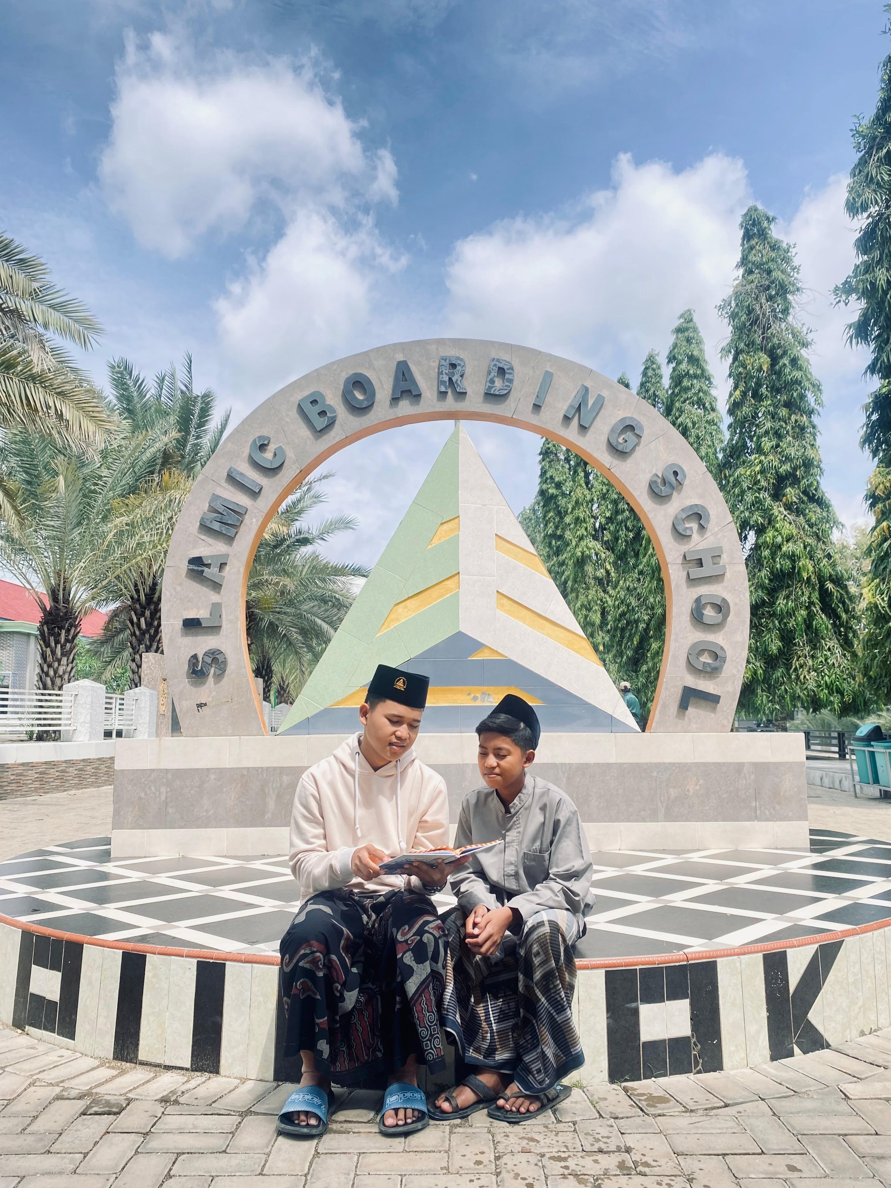 SANTAI: Santri membaca kitab di dekat monumen Ponpes Puncak Darussalam, Selasa (18/3). (MOH. IQBAL AFGANI/JPRM)